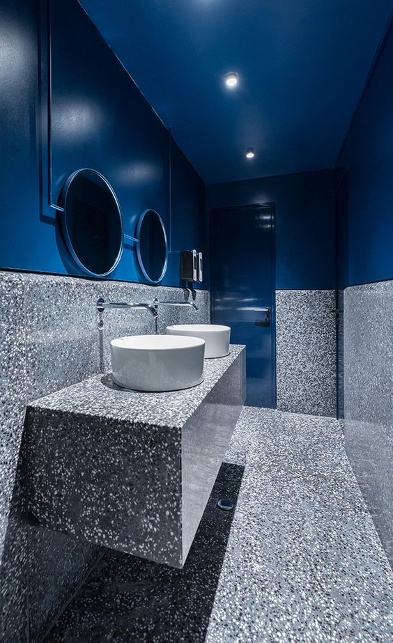 a powder toom in blue and grey stone features not only a color block effect but also a material juxtaposition
