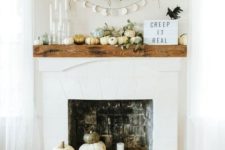 11 a modern and natural mantel with pumpkin, eucalyptus, candles, signs and a fake bird