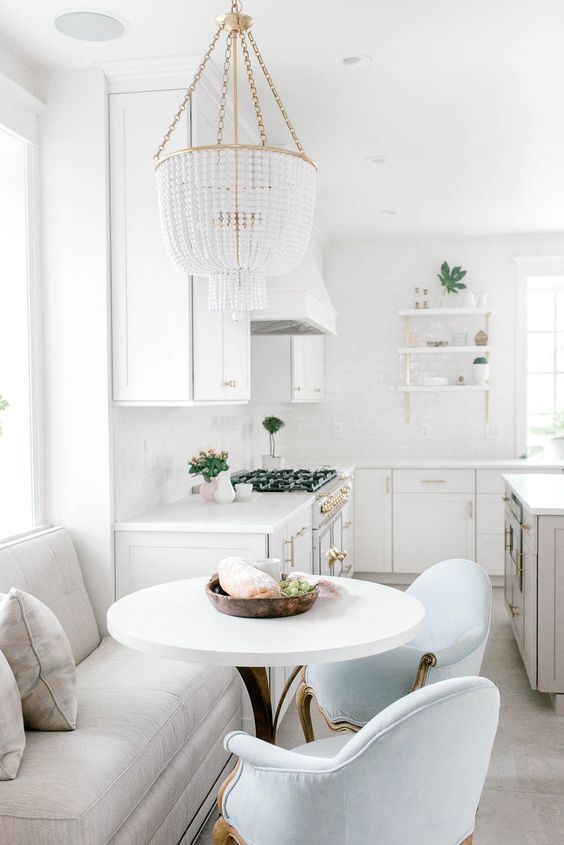 a neutral kitchen with a separate nook for having meals, with comfy refine dchairs and a large banquette seating