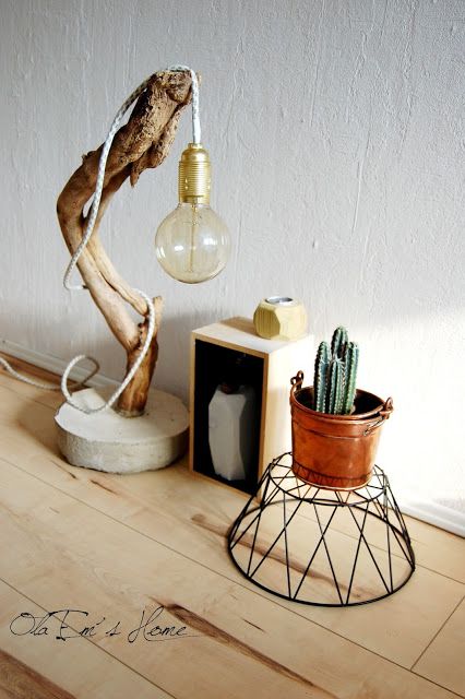An eye catchy table lamp of concrete, a curved tree branch and a large bulb is great for many decor styles