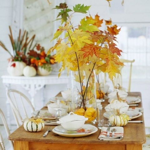 fall leaves in a large sheer vase with pumpkins on the bottom is a modern fall centerpiece