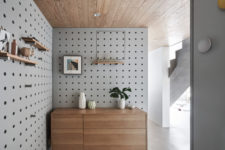 12 The entryway is covered with pegboard and modern furniture, with shelves and potted plants