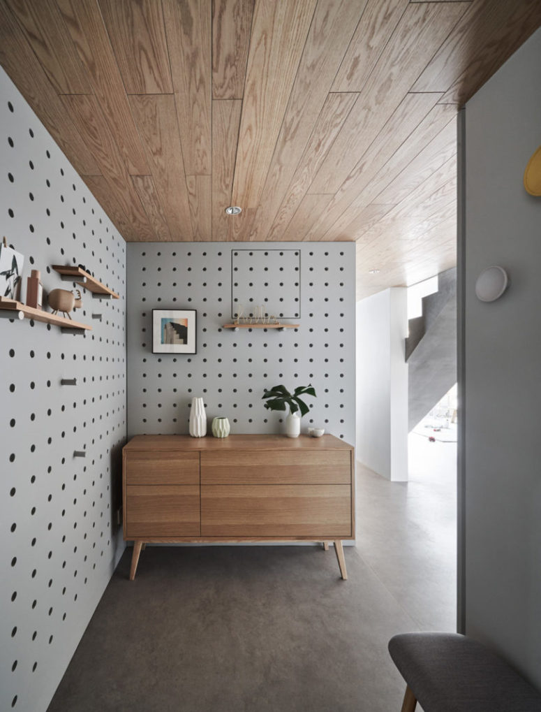 The entryway is covered with pegboard and modern furniture, with shelves and potted plants