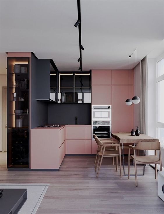 a contemporary color block kitchen in pink and black with a sleek and stylish look and a wooden dining set