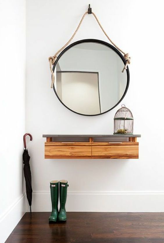 a floating console of wood with a concrete tabletop and a framed mirror with rope for a coastal space