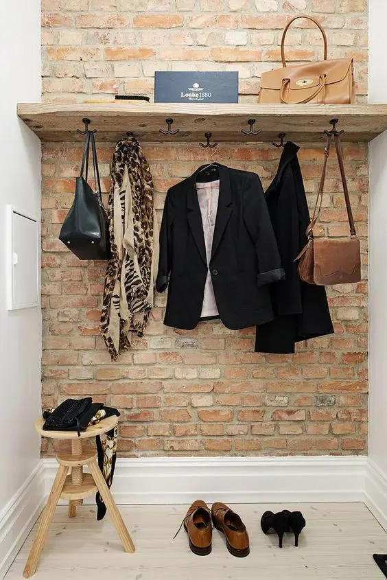 a rustic entryway shelf of rough wood and industrial vintage hooks adds texture and interest to the space