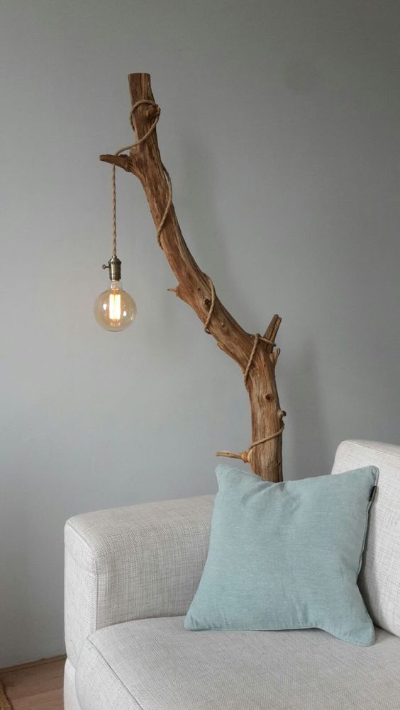 cover a stained tree branch with an industrial pendant light with a cord and a large bulb for making a cool lamp