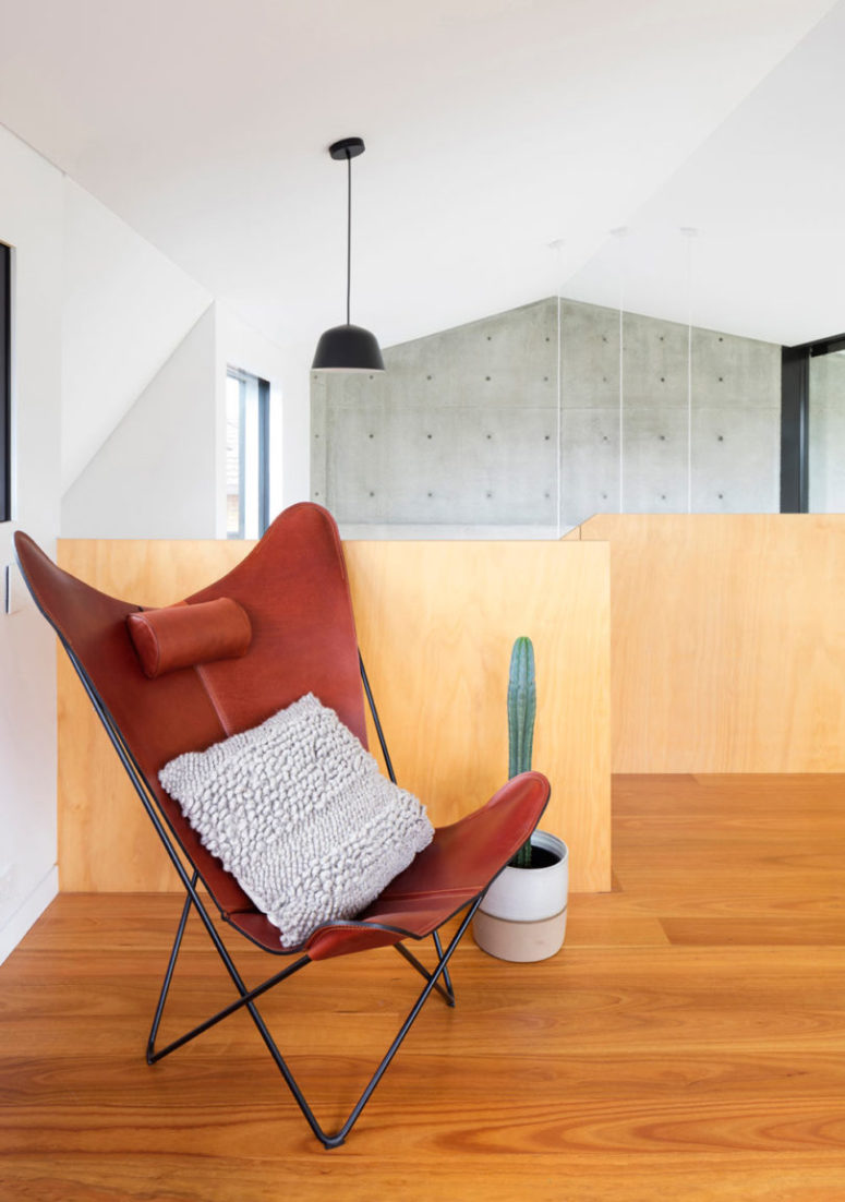 The upper floor meets the owners with a bold red leather chair
