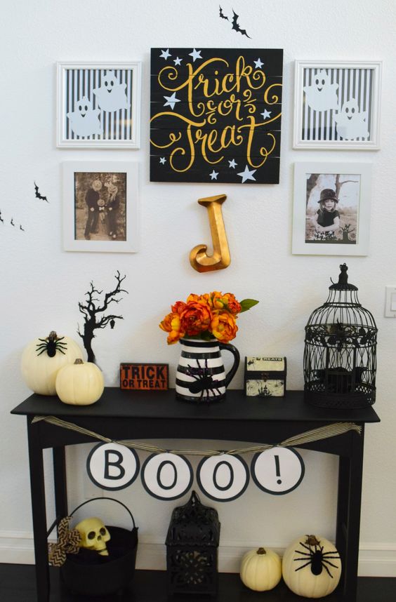 a small console with faux pumpkins, a cage, letters, a psider and some artworks