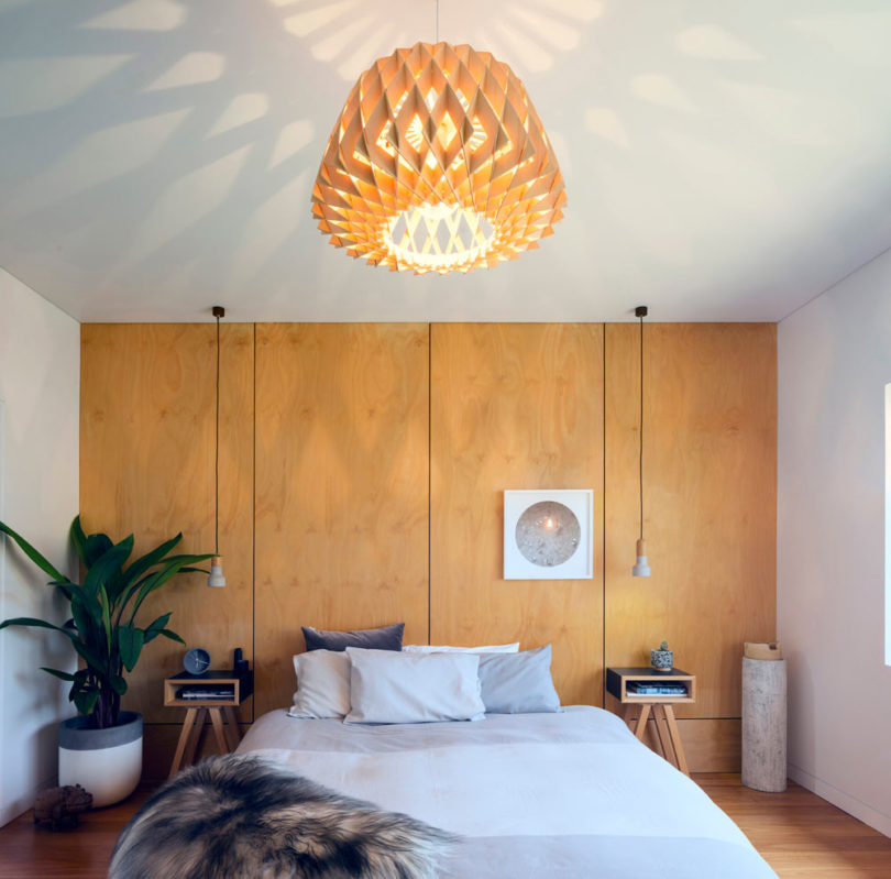The master bedroom is done with pendant lamps and plywood panels plus nightstands