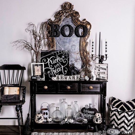 a spooky Halloween console in black and white with painted pumpkins and signs plus a vintage mirror