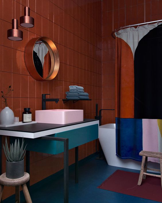 a bold color blocked bathroom with a rust wall, a pink sink, a teal vanity and a color blocked shower curtain to match