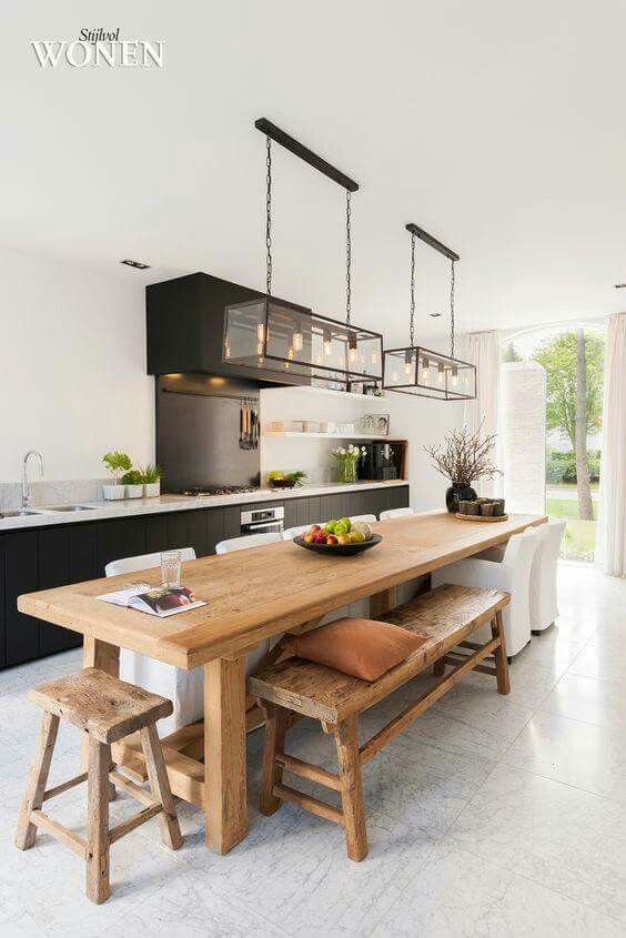a contemporary kitchen is highlighted with a rustic wooden kitchen island, which is also a dining table
