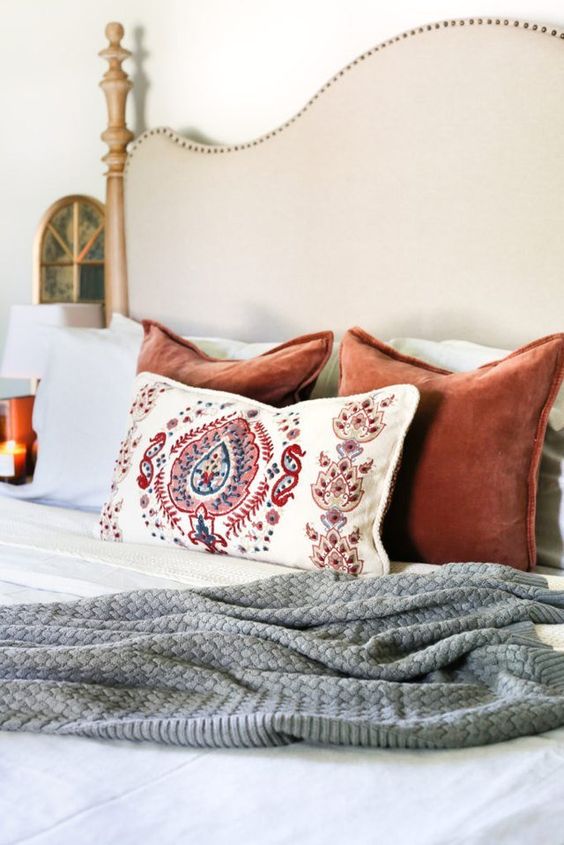 A knit blanket and colorful velvet pillows plus candles for a fall inspired bedroom