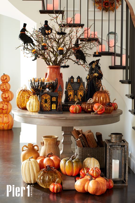 a spooky rustic display with lots of pumpkins in bold shades, cardboard houses and lots of birds
