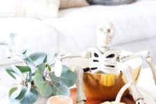 18 a modern fall display with eucalyptus, pumpkins, candles, a skeleton in a gold bowl on a tray