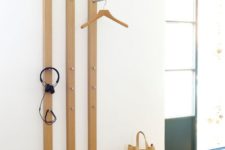 18 a wall-mounted coat rack of wooden slabs and with metal hooks attached here and there to hang the pieces comfortably