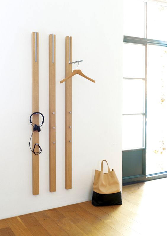 a wall-mounted coat rack of wooden slabs and with metal hooks attached here and there to hang the pieces comfortably