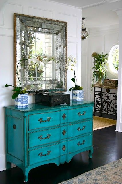 this antique mirror in several metallic frames and a turquoise dresser make an impression in the entryway