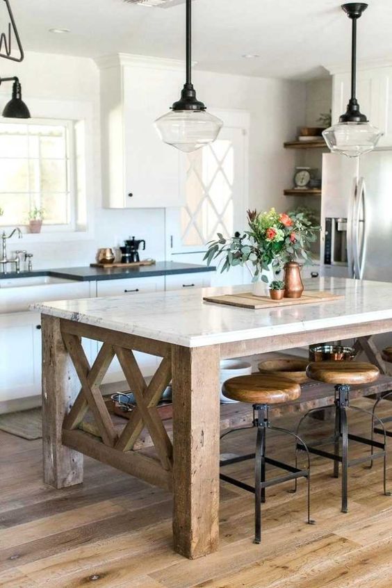 a farmhouse kitchen with a rustic kitchen island of wood and a stone countertop to use as a dining table