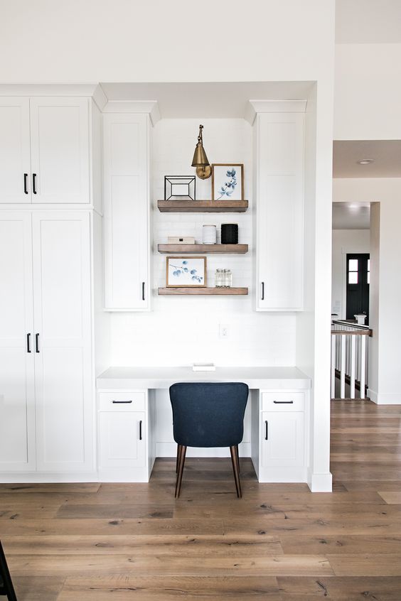 A modern farmhouse space with a seamless home office nook with cabinets, built in shelves and a black chair