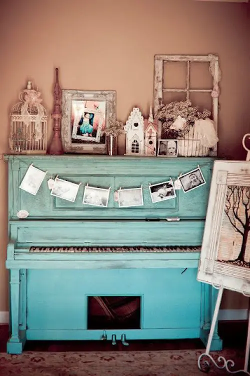 a turquoise piano with a photo bunting and a vintage display of various figurines, frames and other items