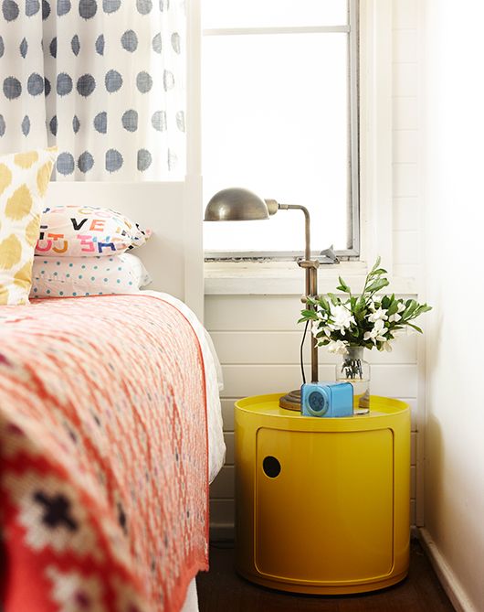 An ultra modern yellow nightstand of a drum shape makes a statement with color