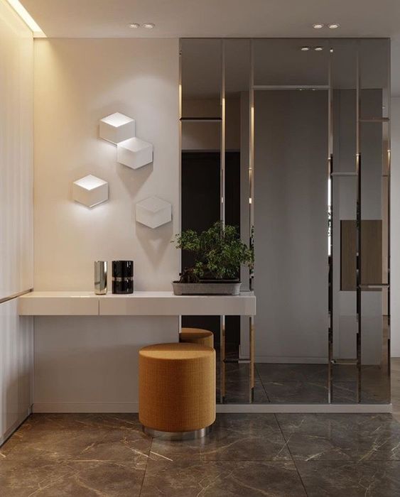 a minimalist entryway with a half mirrored wall, which enlarges the space and makes it bolder