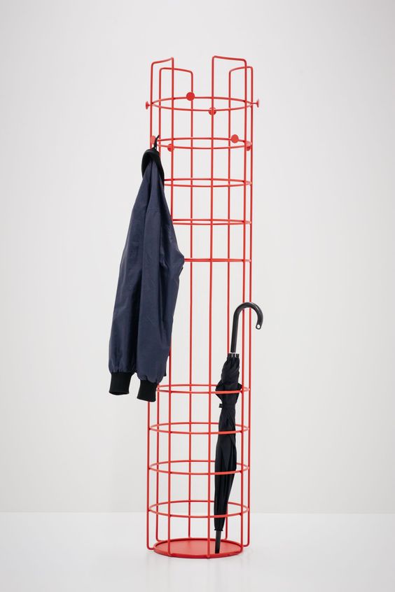a red metal coat rack features several hooks for hanging and enough storage space for your umbrellas