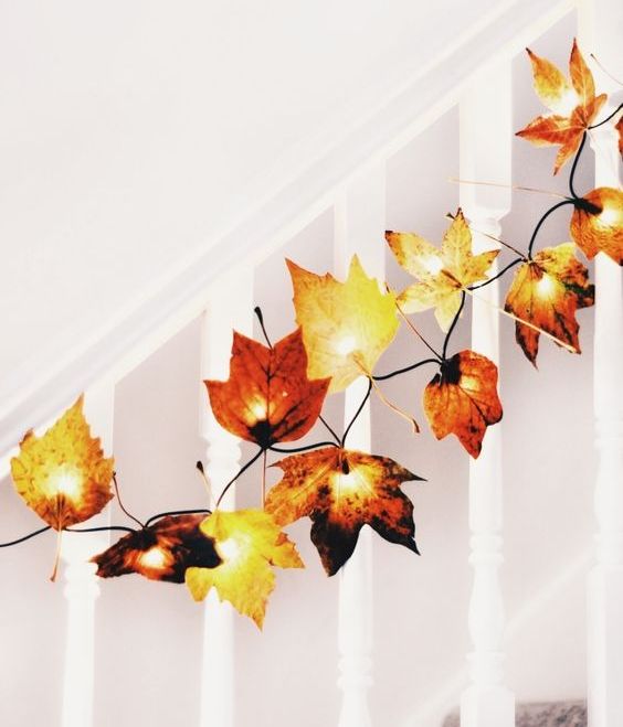 add fake leaves to fairy lights to decorate your home for fall, for example, line up the railing of the stairs