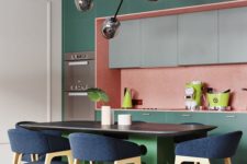 20 dark green cabinets plus a pink backsplash create bold color blocking, a green table and navy chairs add even more color