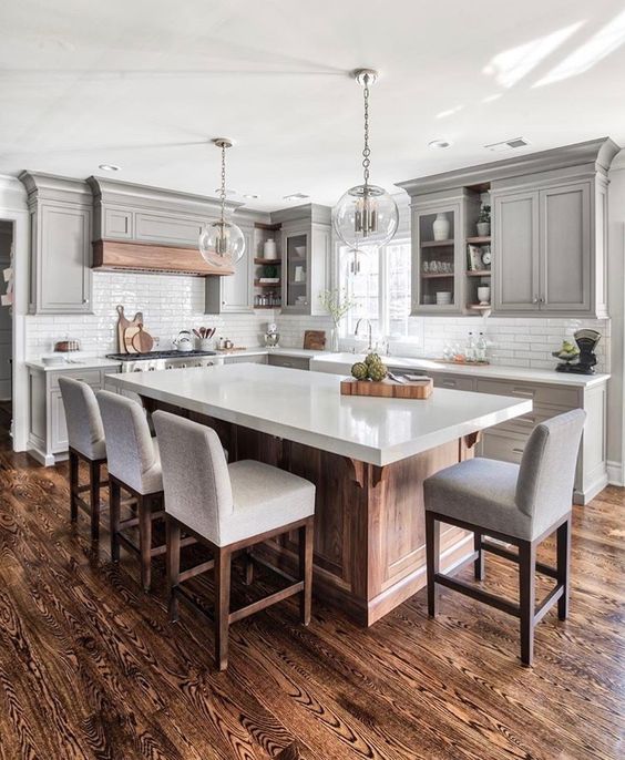 a modern farmhouse kitchen with a large kitchen island of wood and a white ston countertop that doubles as a dining table