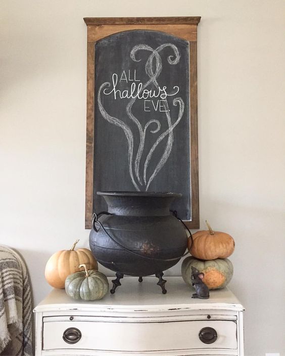 a tiny console table with real pumpkins, a cauldron and a chalkboard sign over the console