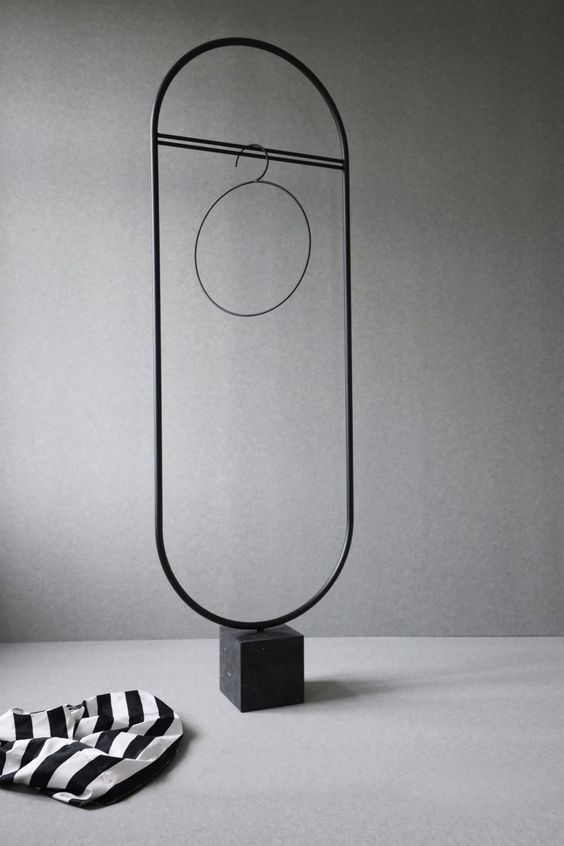 a whimsy yet minimalist coat rack with a stable stone base and a long holder for your clothes