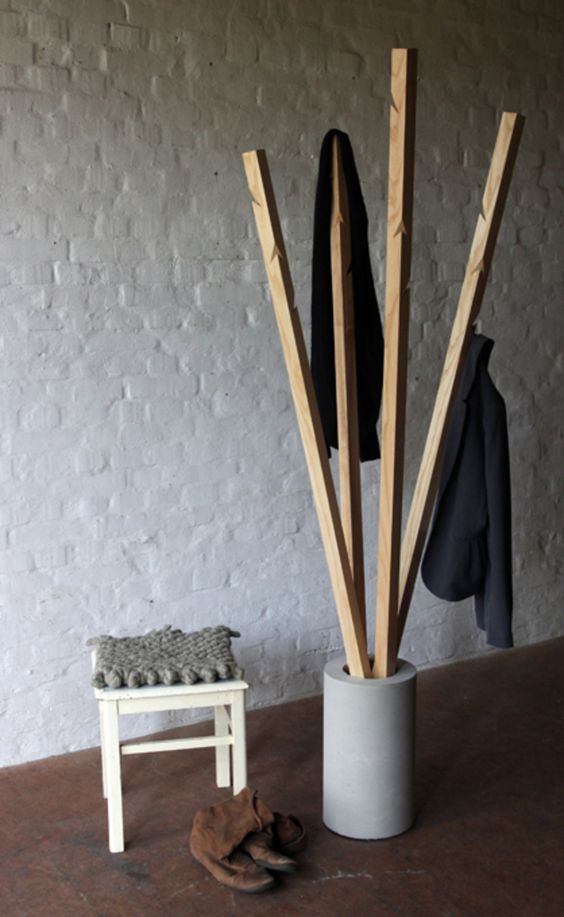 an industrial coat rack with a concrete base and wooden branches with hooks cut in them for a raw touch to your space