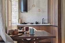 a beautiful and welcoming earthy eat-in kitchen with stained cabinets and matching dining furniture, a black hood and pendant lamps