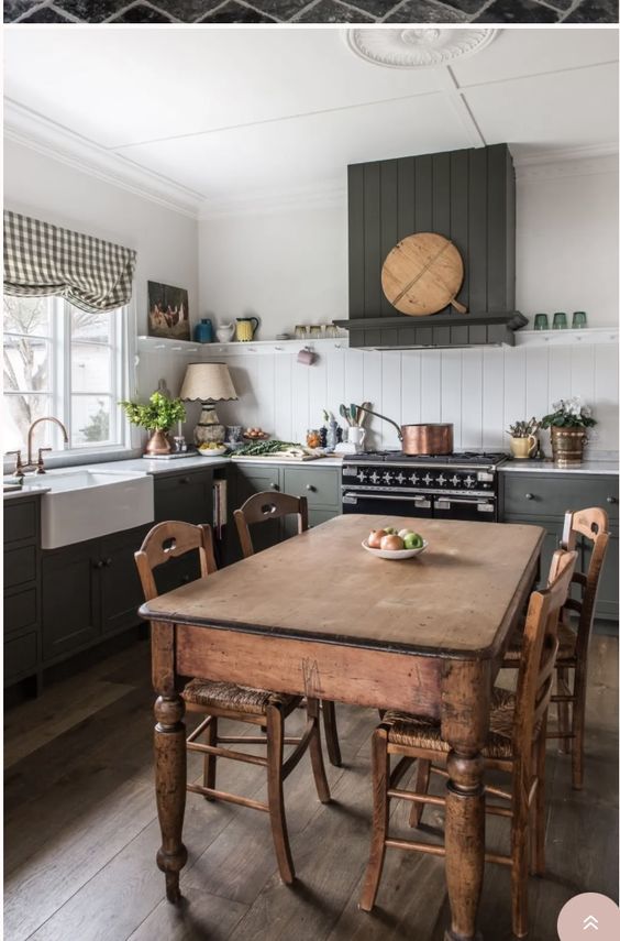 a grey farmhouse kitchen with planked cabinets, a stained vintage dining table and chairs, a planked backsplash