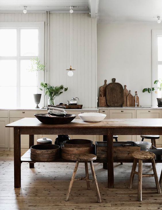 a lovely farmhouse kitchen in tan, with planked walls and a dark-stained dining furniture set is welcoming