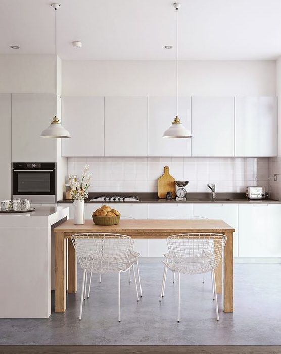 a minimalist kitchen in white, with a black countertop, a small wooden table for a contrast and a soft touch and metal chairs