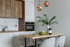 a minimalist kitchen with white and wood cabinetry, pendant lamps, a wooden table and grey chairs is very chic