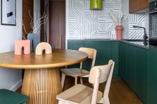 a modern and colorful kitchen with dark green and stained cabinets, a geo tile backsplash, a large table and mismatching chairs