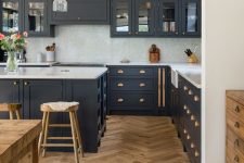 a modern farmhouse kitchen with navy cabinets, a white backsplash and countertops, a chic herringbone floor and a matching table