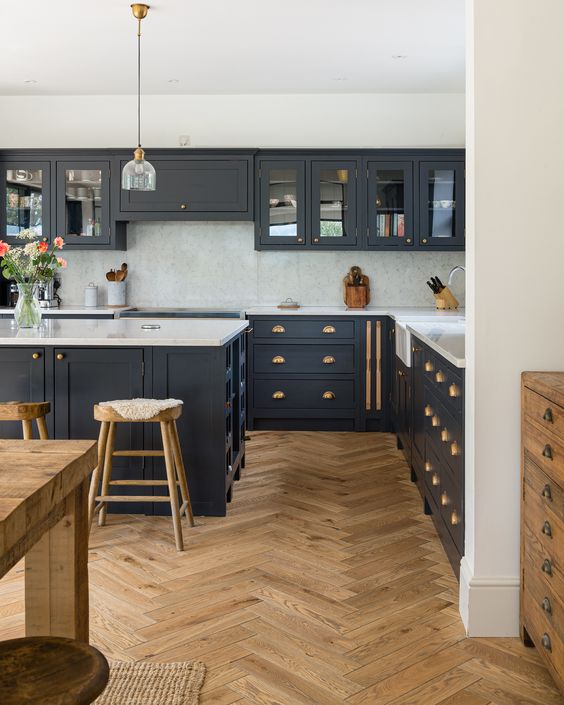 a modern farmhouse kitchen with navy cabinets, a white backsplash and countertops, a chic herringbone floor and a matching table
