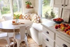 a neutral cottage eat-in kitchen with stone countertops and a dining corner, a corner bench, a round table and metal chairs