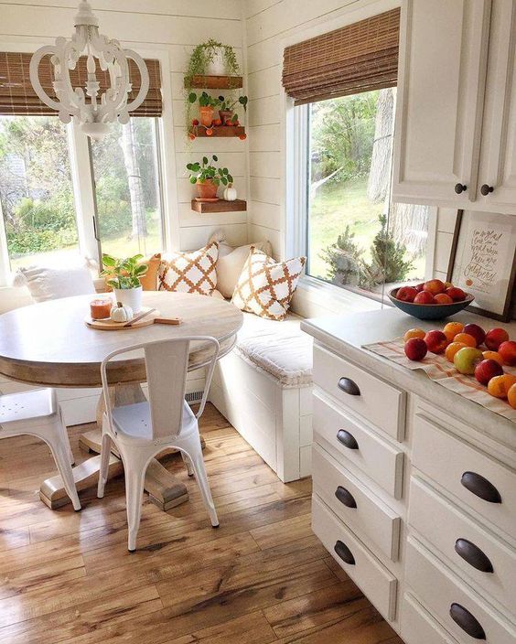 A neutral cottage eat in kitchen with stone countertops and a dining corner, a corner bench, a round table and metal chairs