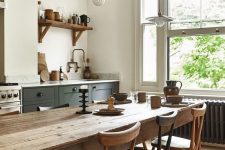 a pretty rustic meets Scandinavian kitchen with dark green cabinets, a stained dining set with matching chairs and pendant lamps