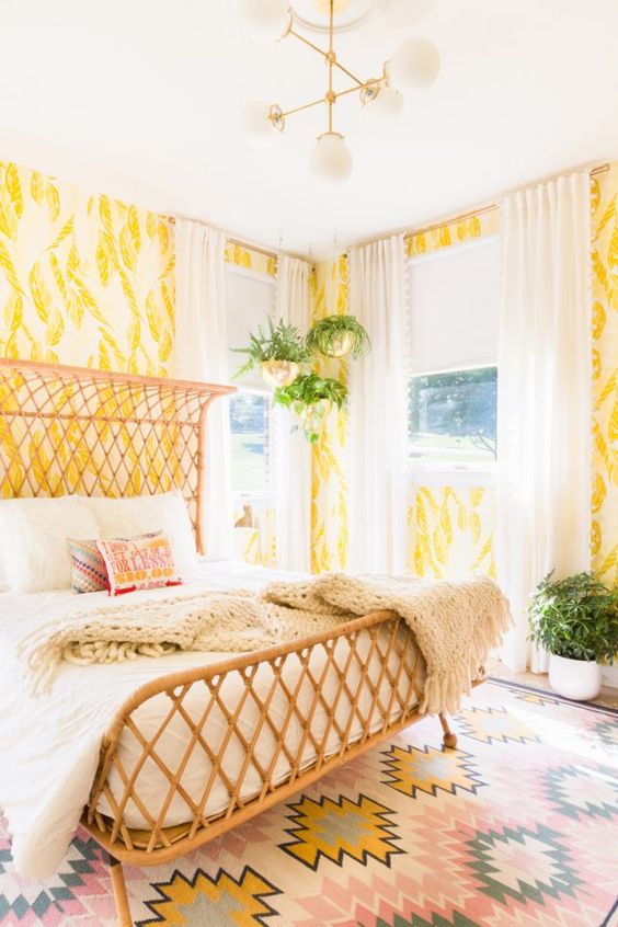 bold yellow and white wallpaper with botanical prints create a bright space and a wicker bed adds to it