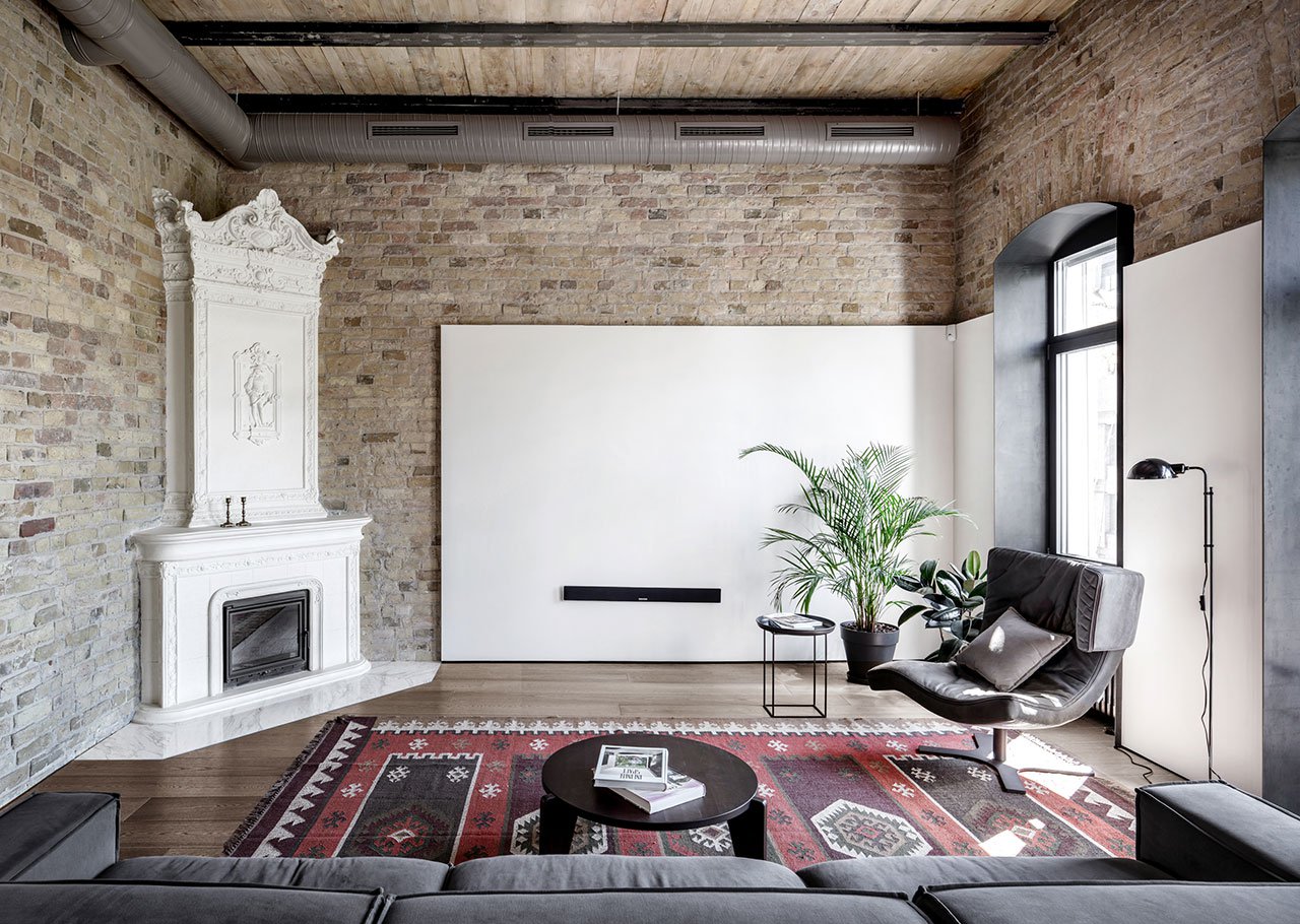 The living room features comfy furniture, a vintage hearth with a built in modern fireplace and original brick clad