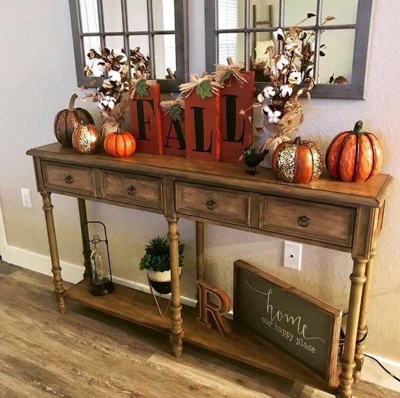 a bright fall console with fake pumpkins, cotton arrangements and wooden letters in bright orange