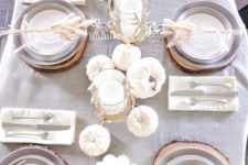 02 a chic neutral table setting with a grey tablecloth, white pumpkins and candles and feathers for each place setting